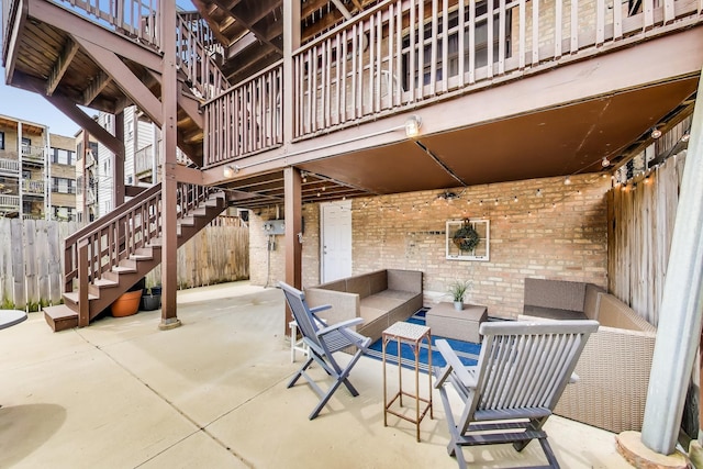 view of patio with an outdoor living space, fence, and stairway