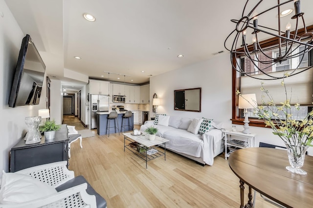 living room featuring a chandelier, recessed lighting, light wood-style flooring, and visible vents