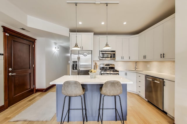 kitchen with a sink, light countertops, stainless steel appliances, and light wood-style flooring