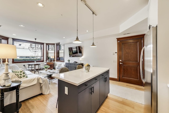 kitchen with freestanding refrigerator, pendant lighting, light wood-type flooring, light countertops, and a center island