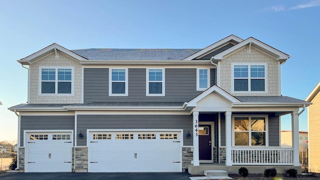 craftsman house featuring a porch, driveway, roof with shingles, an attached garage, and stone siding