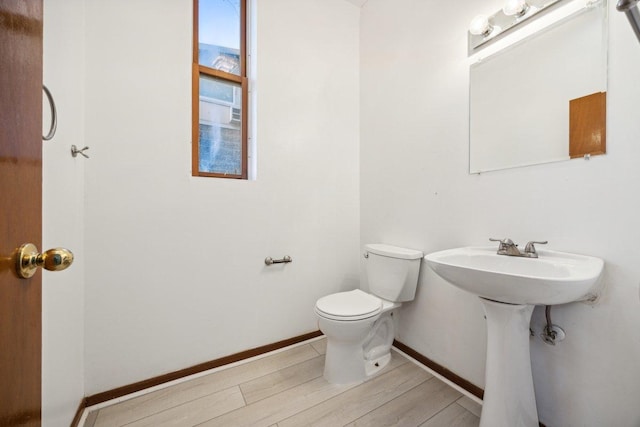 bathroom with baseboards, wood finished floors, and toilet