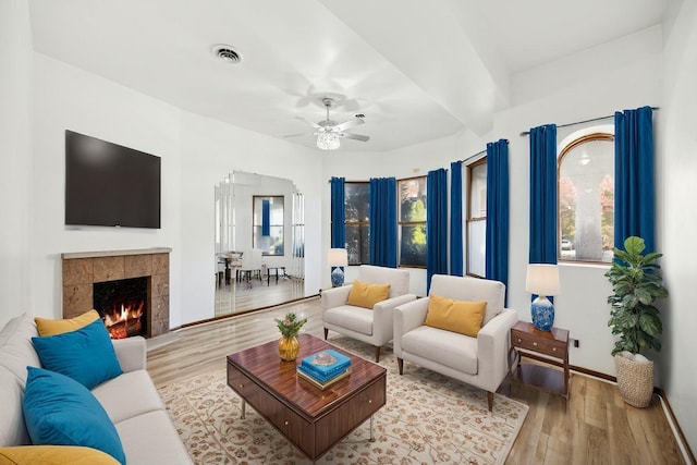living room with a fireplace, a ceiling fan, baseboards, wood finished floors, and visible vents