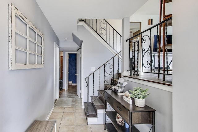 entrance foyer with baseboards, stairs, and tile patterned flooring