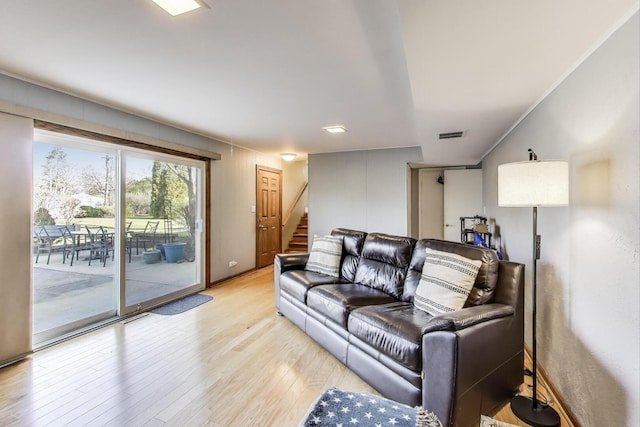 living room with visible vents, light wood-style flooring, and stairway