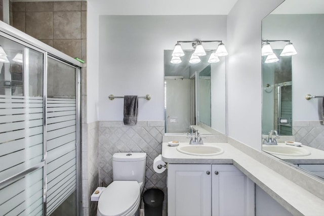 full bathroom with a sink, a stall shower, toilet, and tile walls
