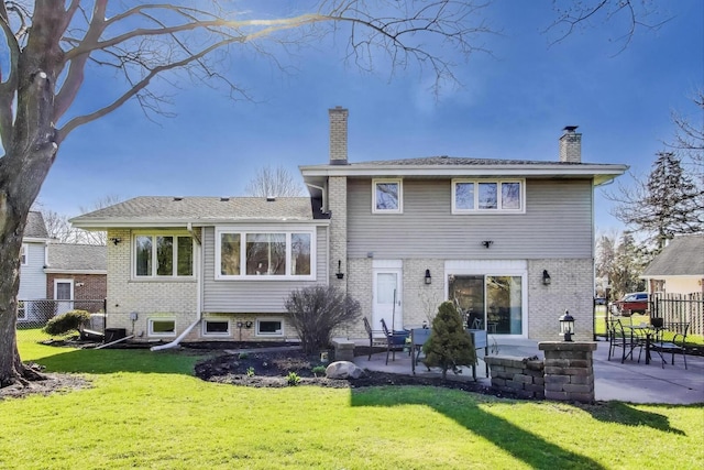 rear view of property featuring fence, a chimney, a yard, and a patio area