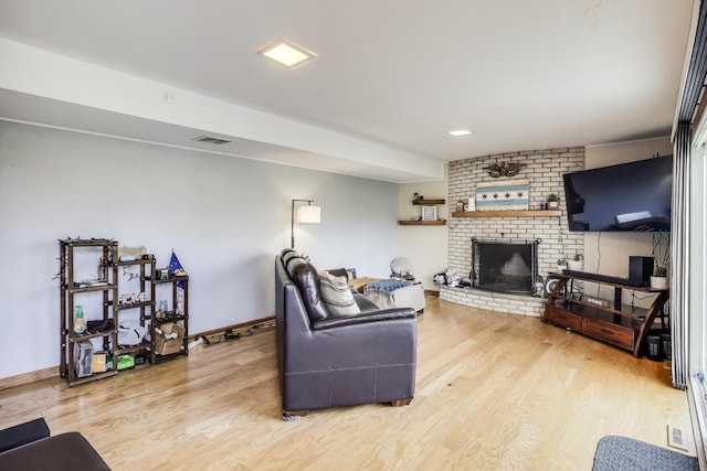 living area with a fireplace, baseboards, visible vents, and light wood-style floors