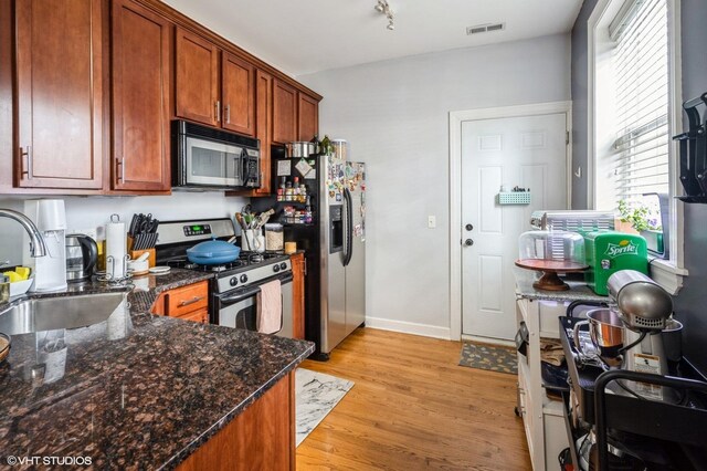 534 W Belmont Ave Unit 2S, Chicago, IL 60657 - kitchen with a sink, light wood-style floors, dark stone counters, stainless steel appliances, and visible vents