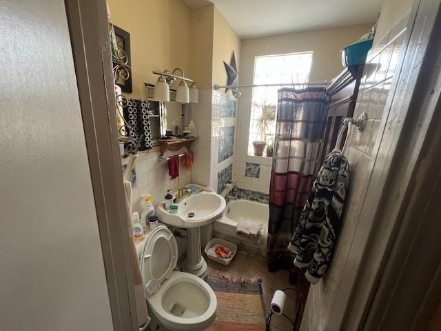 full bath featuring a sink, toilet, shower / bath combination with curtain, tile walls, and decorative backsplash
