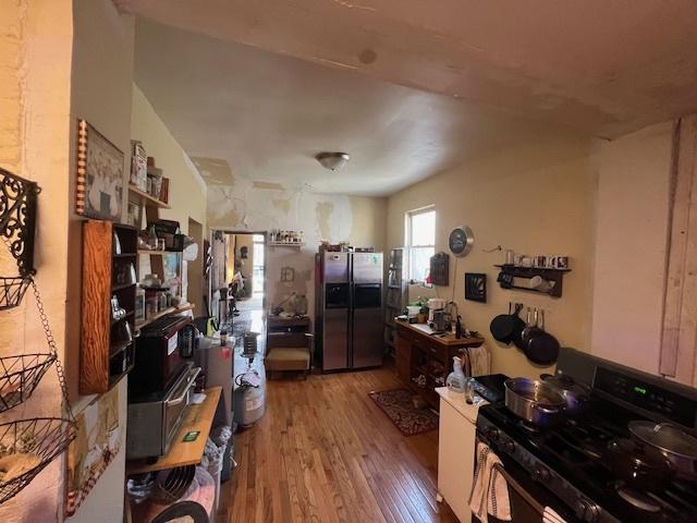 kitchen with hardwood / wood-style floors, stainless steel fridge with ice dispenser, and gas range