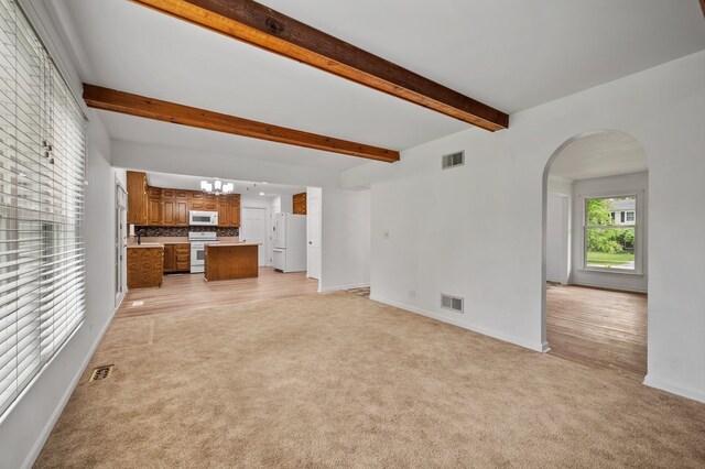 848 Stewart St, Batavia, IL 60510 - unfurnished living room featuring light colored carpet, arched walkways, baseboards, beamed ceiling, and a chandelier