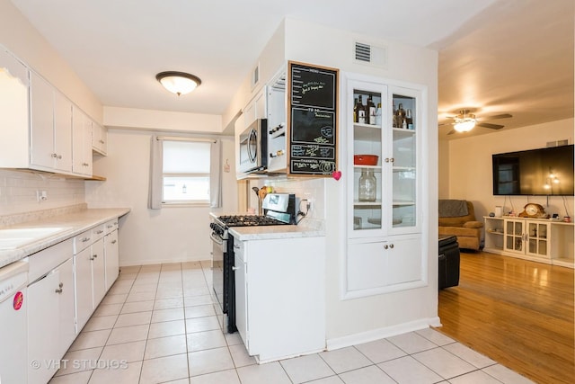 224 Howard Ave, East Dundee, IL 60118 - kitchen with stainless steel appliances, backsplash, light tile patterned flooring, light countertops, and white cabinets