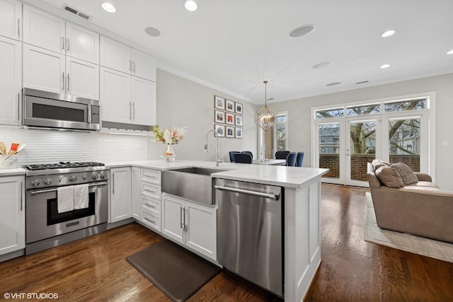 kitchen with visible vents, a peninsula, light countertops, a sink, and appliances with stainless steel finishes
