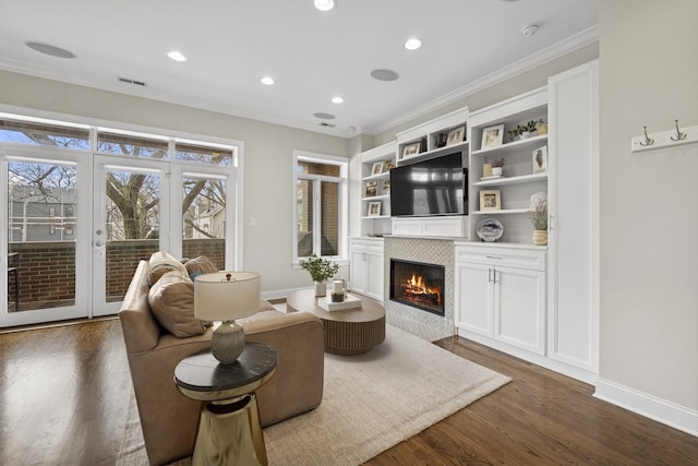 living area with visible vents, ornamental molding, a tile fireplace, and dark wood-type flooring