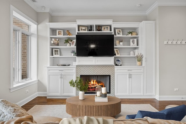 living room featuring baseboards, ornamental molding, wood finished floors, and a tiled fireplace