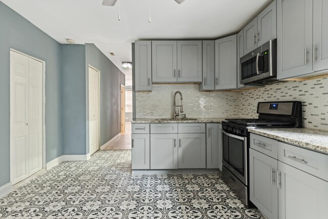 kitchen featuring a sink, decorative backsplash, gray cabinetry, and stainless steel appliances
