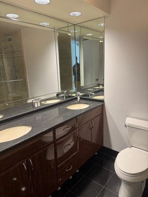 360 E Randolph St Unit 302, Chicago, IL 60601 - bathroom featuring tile patterned floors, double vanity, toilet, a tile shower, and baseboards