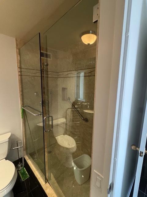 bathroom featuring toilet, tile patterned floors, and a shower stall