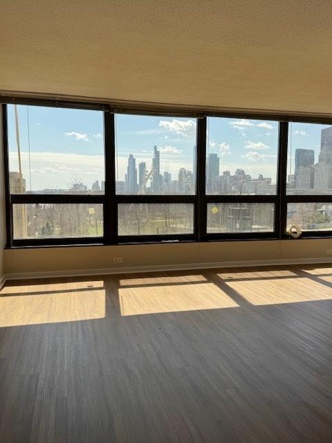 unfurnished room featuring a view of city, baseboards, and wood finished floors