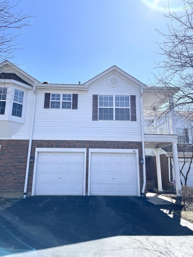view of front of property with brick siding, a garage, and aphalt driveway