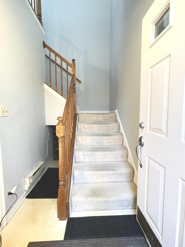 staircase with baseboards and a baseboard heating unit