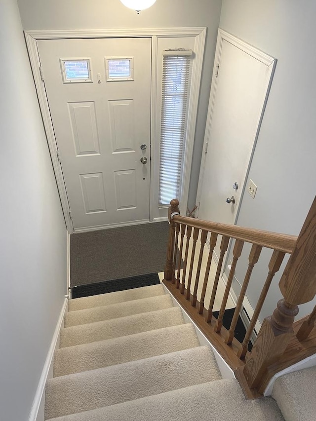 carpeted foyer with stairs and baseboards