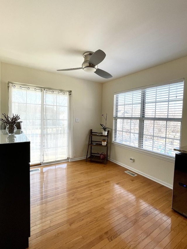 spare room featuring visible vents, light wood finished floors, ceiling fan, and baseboards