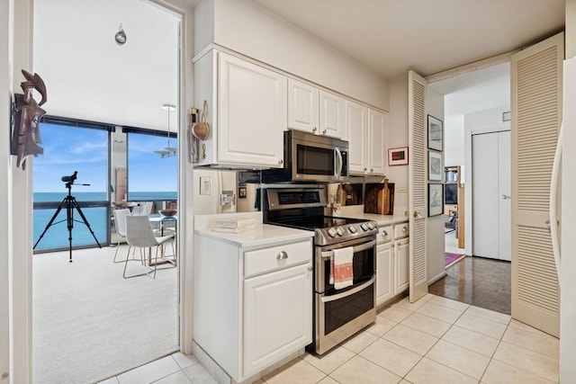 1240 N Lake Shore Dr Unit 9B, Chicago, IL 60610 - kitchen featuring light colored carpet, appliances with stainless steel finishes, light countertops, light tile patterned floors, and white cabinetry