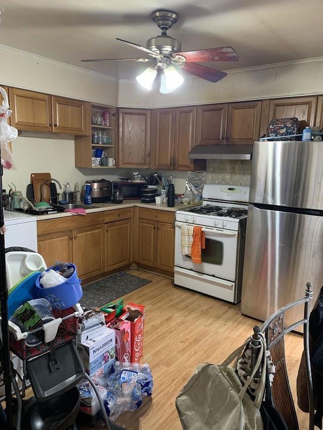 kitchen featuring ceiling fan, light countertops, white gas range oven, freestanding refrigerator, and under cabinet range hood