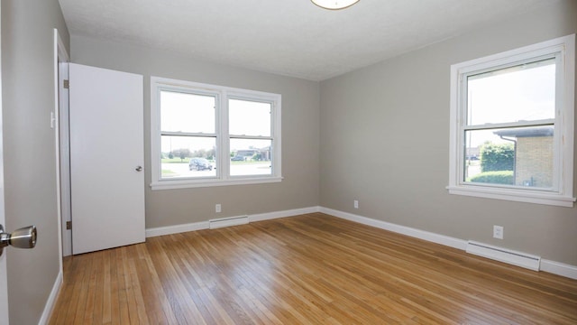 1201 S Mercer Ave, Bloomington, IL 61701 - empty room with a baseboard radiator, light wood-style flooring, and baseboards
