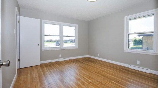 1201 S Mercer Ave, Bloomington, IL 61701 - unfurnished room with baseboard heating, baseboards, and light wood-style flooring