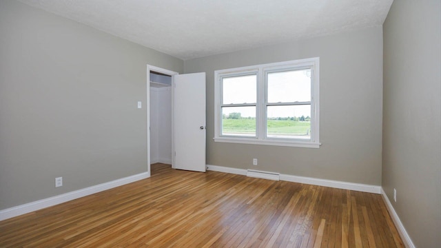 1201 S Mercer Ave, Bloomington, IL 61701 - unfurnished bedroom featuring a baseboard radiator, light wood finished floors, and baseboards