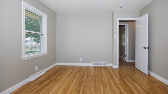 1201 S Mercer Ave, Bloomington, IL 61701 - unfurnished room with light wood-style flooring, baseboards, a baseboard heating unit, and a smoke detector