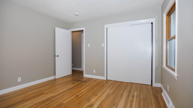 1201 S Mercer Ave, Bloomington, IL 61701 - unfurnished bedroom with light wood-type flooring, a closet, and baseboards