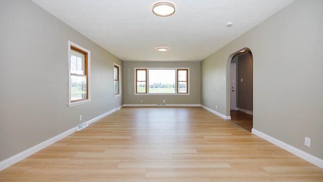 1201 S Mercer Ave, Bloomington, IL 61701 - unfurnished room featuring arched walkways, light wood-style floors, and baseboards