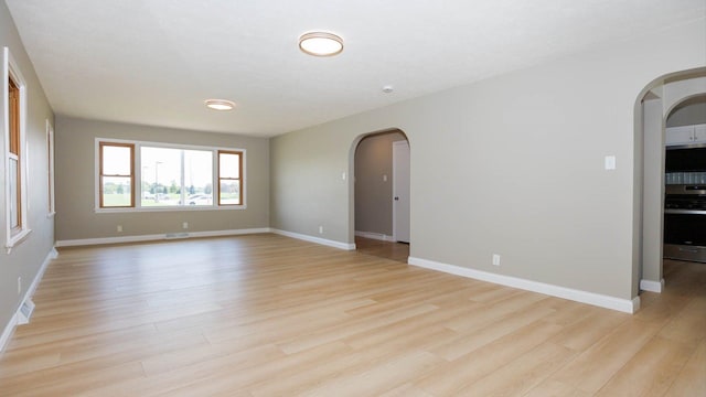 1201 S Mercer Ave, Bloomington, IL 61701 - unfurnished room featuring arched walkways, light wood finished floors, and baseboards