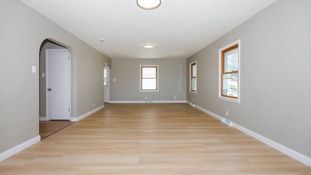 1201 S Mercer Ave, Bloomington, IL 61701 - empty room with arched walkways, light wood-style flooring, and baseboards