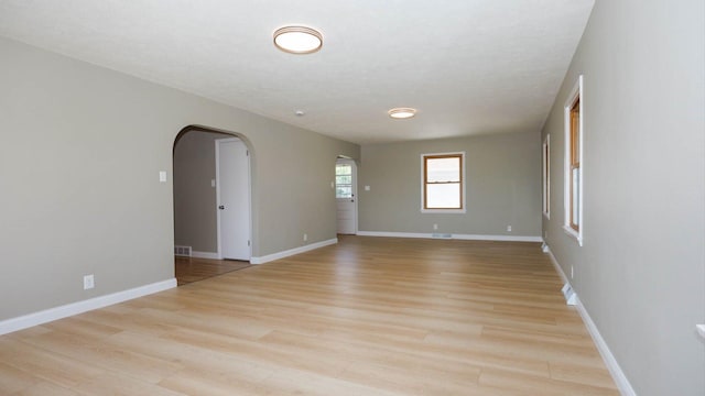 1201 S Mercer Ave, Bloomington, IL 61701 - spare room with arched walkways, light wood-style flooring, and baseboards