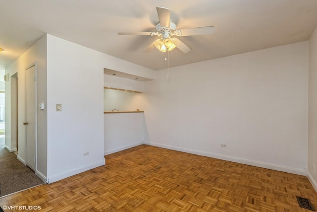 empty room featuring baseboards, ceiling fan, and visible vents