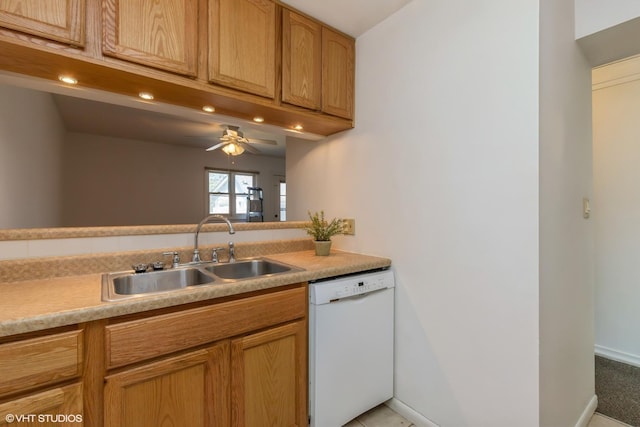 kitchen with a ceiling fan, baseboards, white dishwasher, light countertops, and a sink