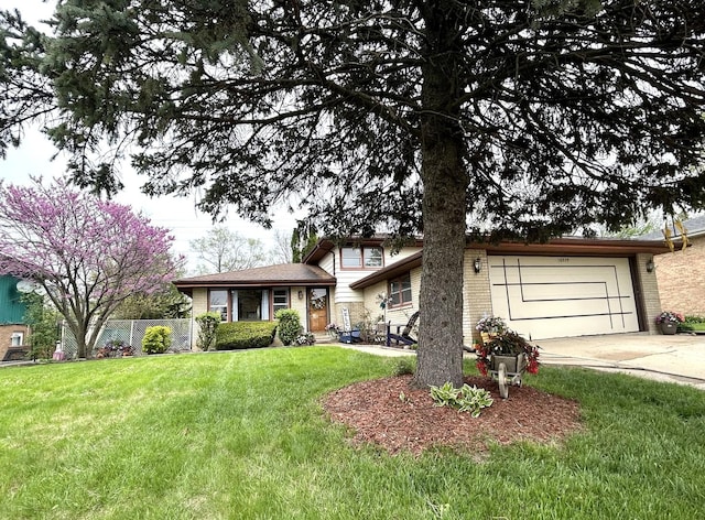 split level home featuring concrete driveway, an attached garage, fence, and a front lawn