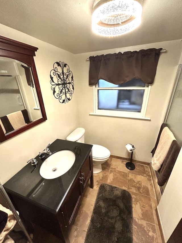 bathroom featuring toilet, stone finish flooring, and vanity