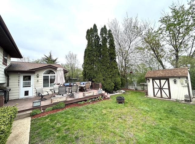 view of yard with an outdoor structure, a deck, a shed, and an outdoor living space with a fire pit