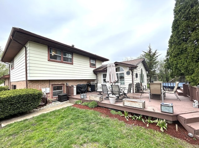 rear view of house featuring a wooden deck, outdoor dining space, and a yard