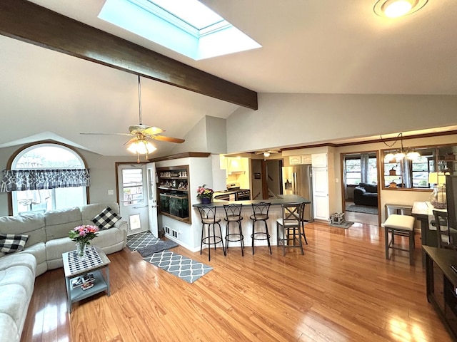 living area with a ceiling fan, a skylight, plenty of natural light, and light wood finished floors