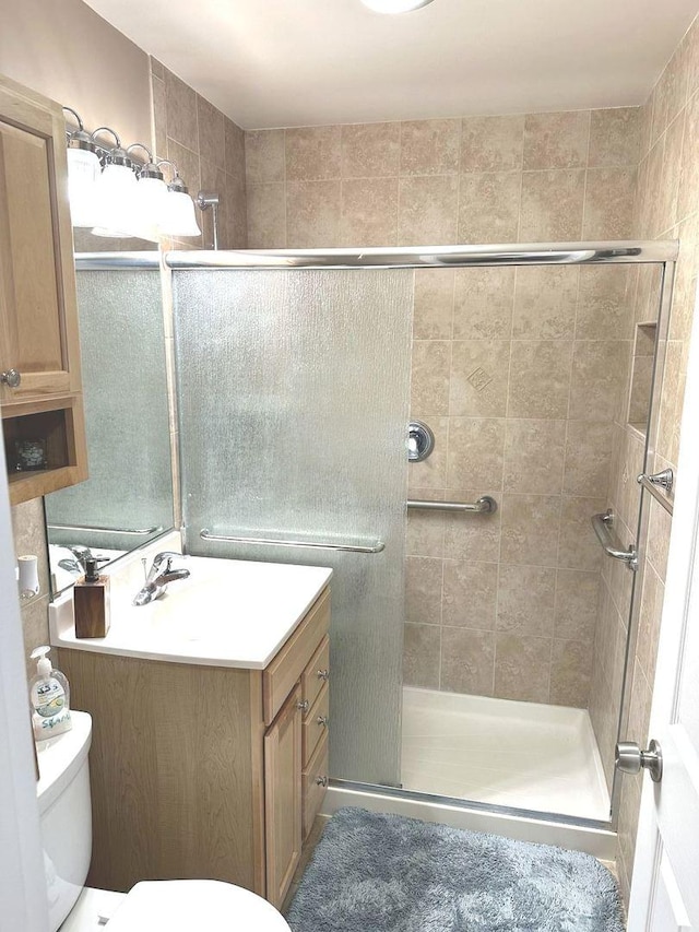 full bathroom with vanity, a stall shower, and toilet