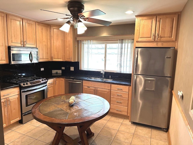 kitchen featuring a sink, dark countertops, light tile patterned floors, and stainless steel appliances