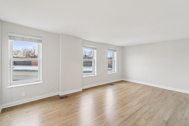 unfurnished room featuring visible vents, light wood finished floors, and baseboards