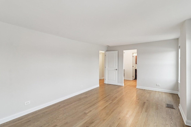 spare room featuring baseboards, light wood-style flooring, and visible vents